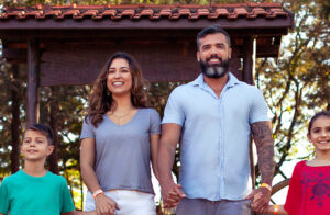 fotografia de uma família branca de quatro pessoas, sendo um homem, uma mulher e duas crianças todos de mãos dadas