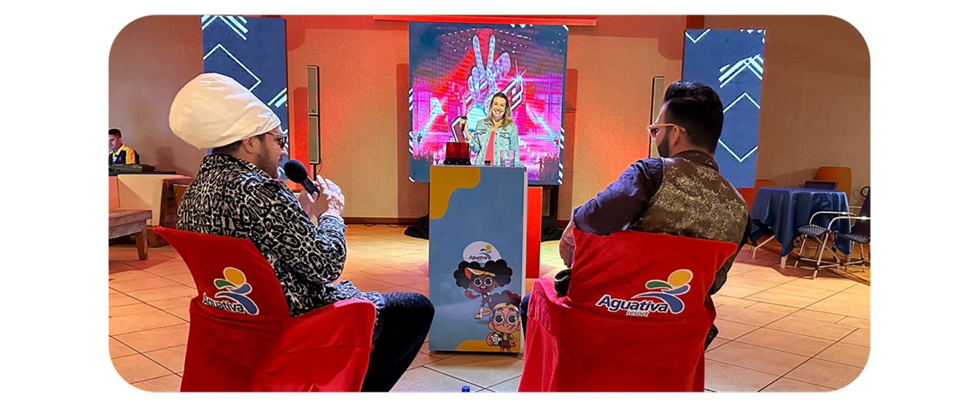 Participante se apresenta em show de talentos com jurados fantasiados, em ambiente animado no Aguativa Resort.