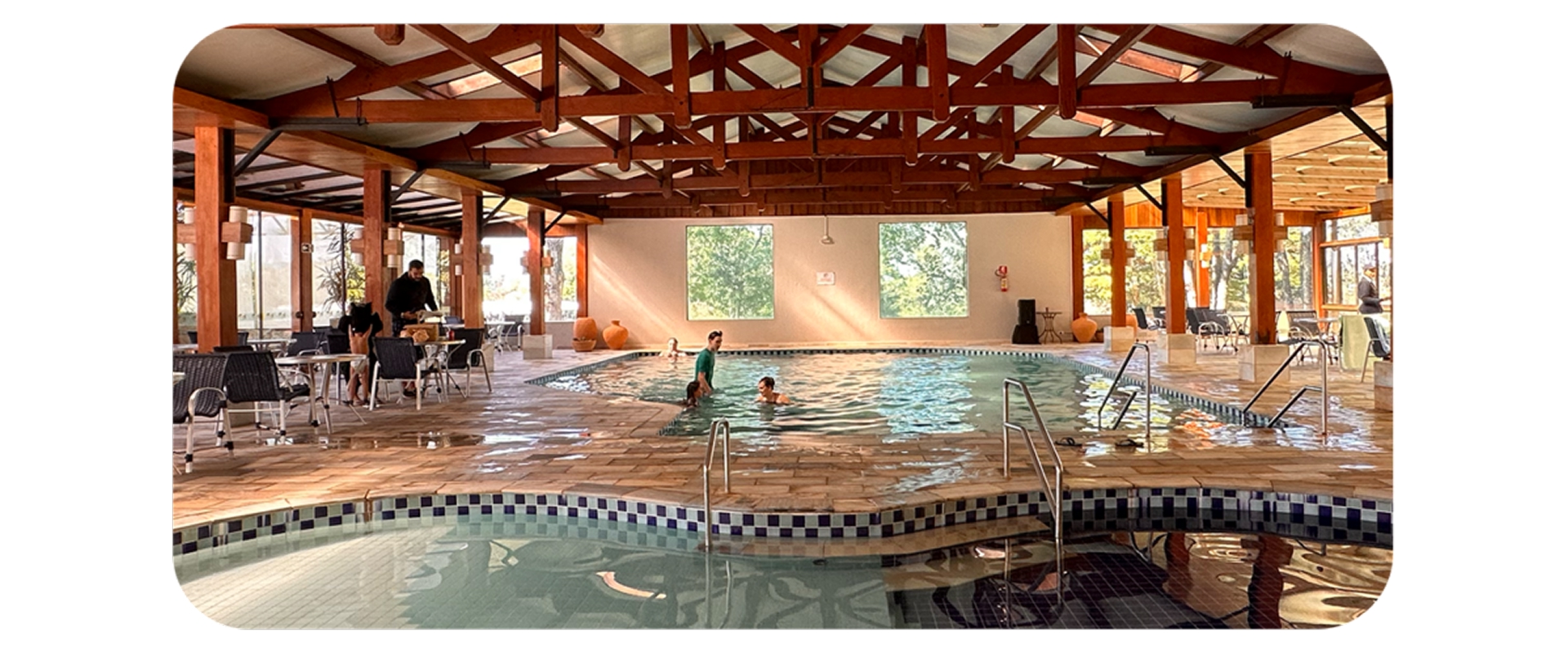 Famílias aproveitando a piscina aquecida coberta do Aguativa Golf Resort em ambiente com estrutura de madeira.