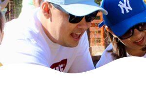 Família sorridente brincando ao ar livre com crianças em ambiente ensolarado e cercado por natureza.