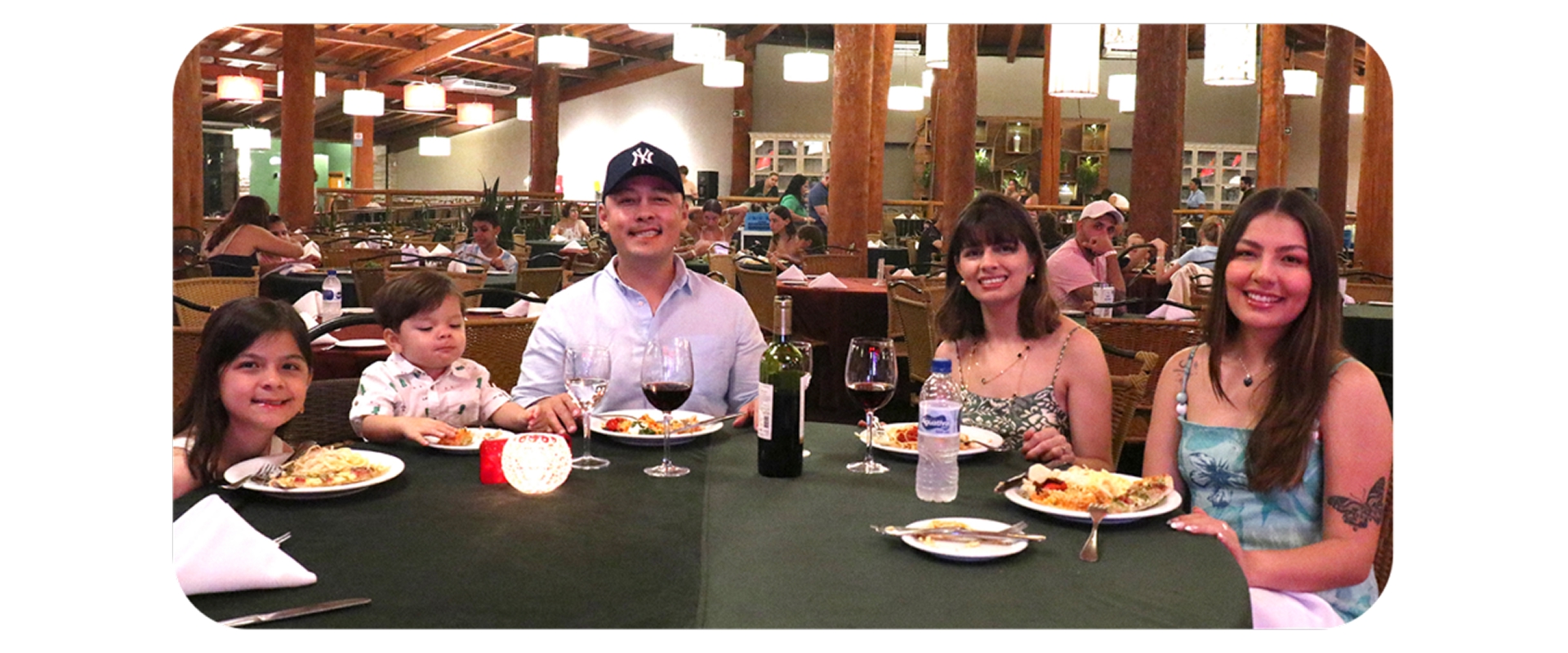 Família janta reunida em restaurante aconchegante com iluminação quente e ambiente rústico.