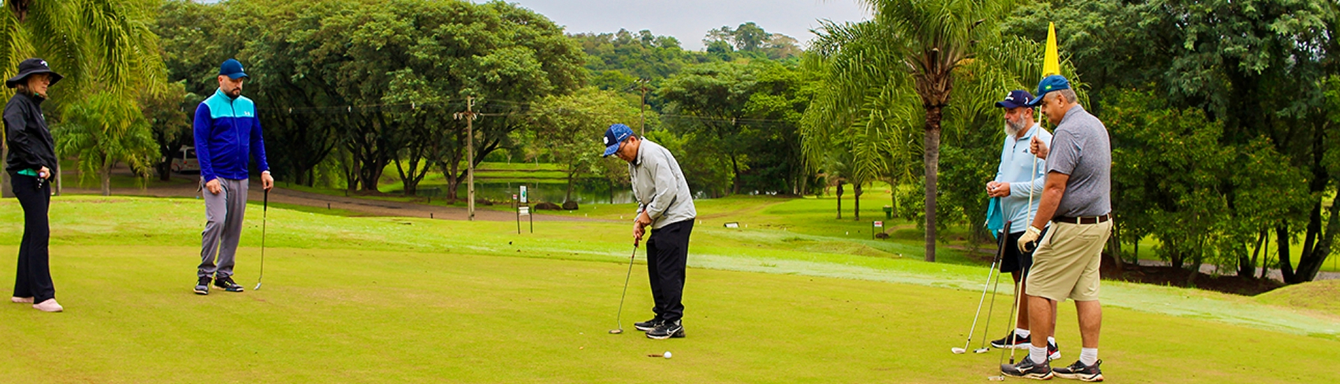 Grupo de golfistas praticando no green de um campo de golfe rodeado por árvores no Aguativa Golf Resort.